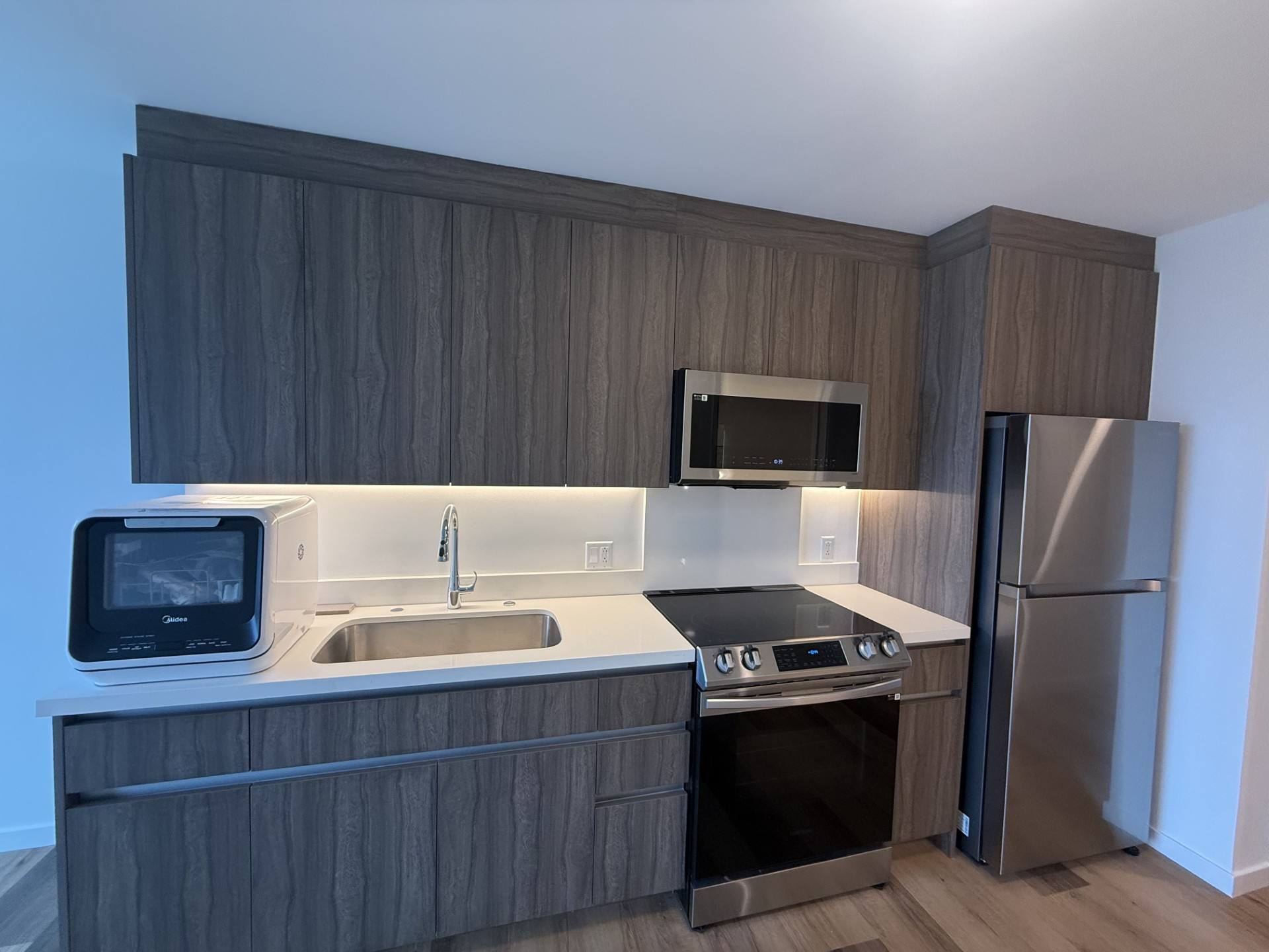 A kitchen with a sink, microwave, oven, and refrigerator.